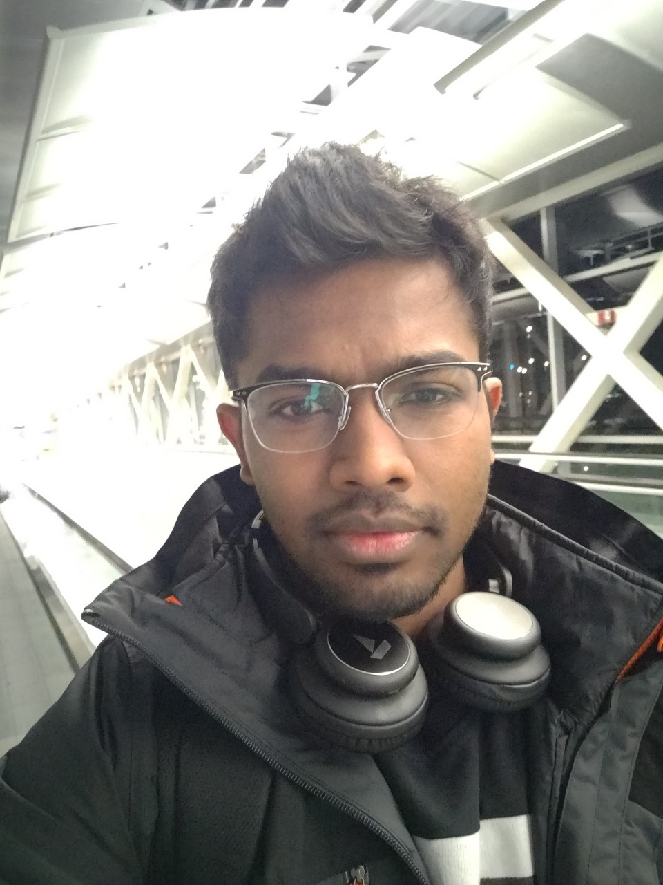 A selfie of Iniyan wearing glasses and headphones around his neck.