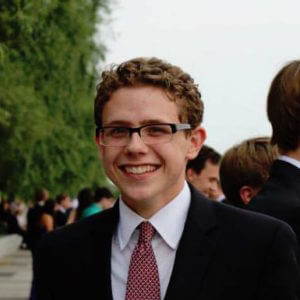 A picture of Tanner Lambson wearing a suit with a red tie.