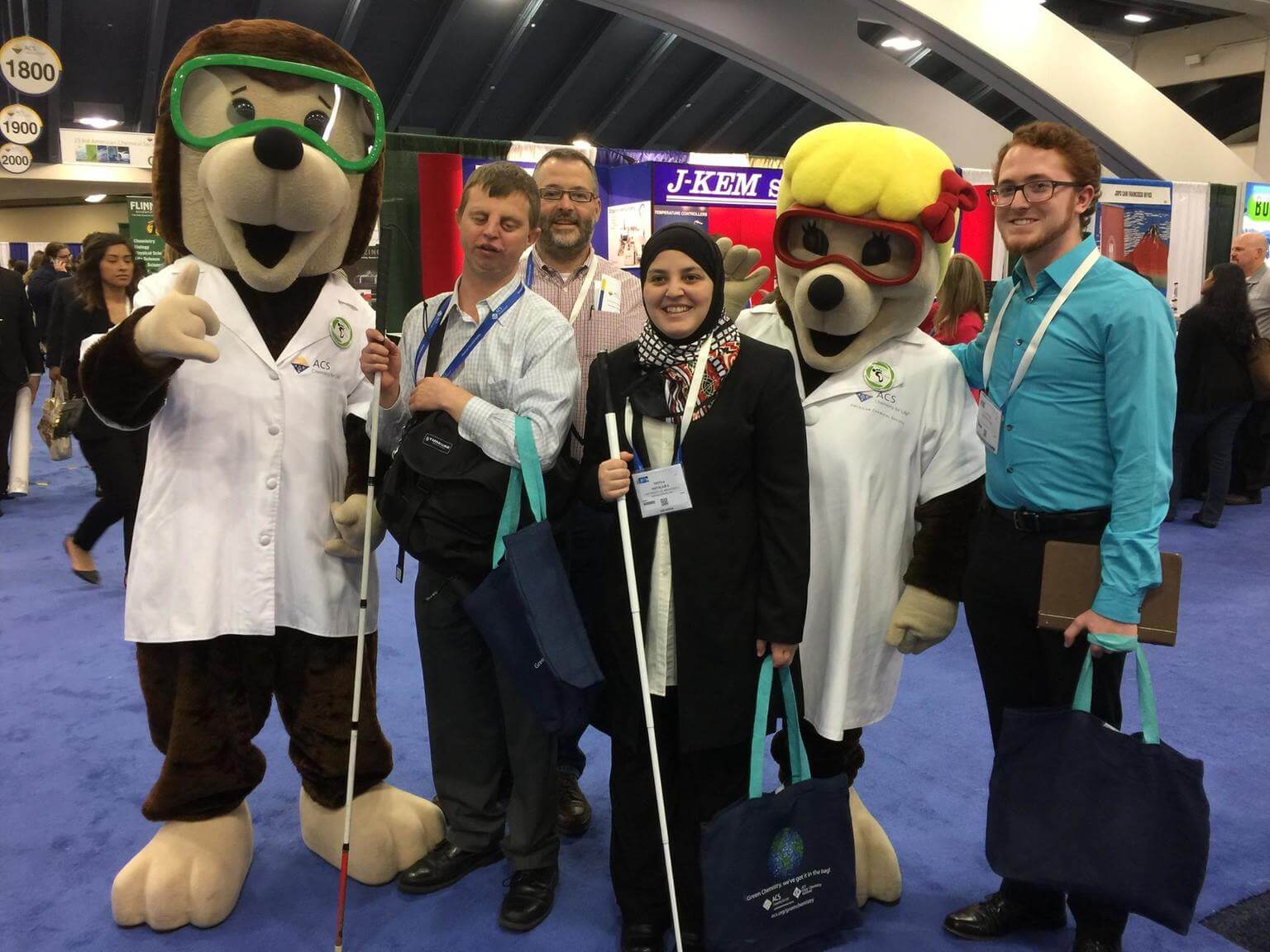 Mona Minkara and other chemists pose with ACS Mascots dressed in dog costumes. Mona and the chemist next to her both hold their canes.