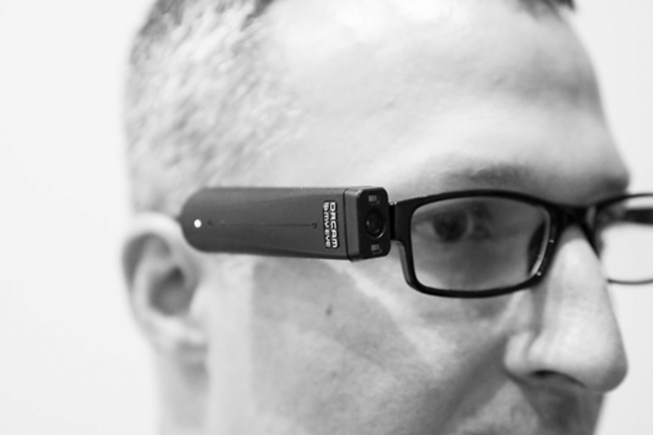 An image of an Orcam, a pair of glasses connected to a black battery pack. 