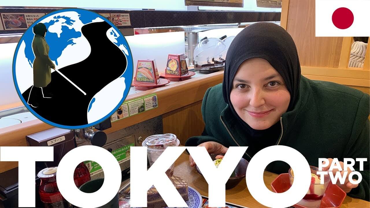 A thumbnail for Traveling Blind in Japan - Planes, Trains and Canes Episode 5 Part 2. It shows Mona smiling over a meal infront of a sushi conveyer belt. Superimposed on the image is the PTC Logo and a flag of Japan.
